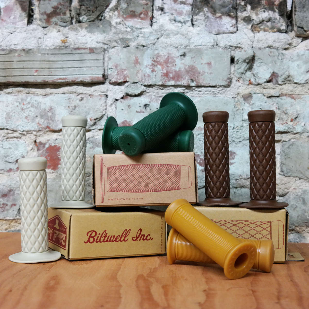 Boxes of Biltwell Inc. handle grips on a table next to a brick wall